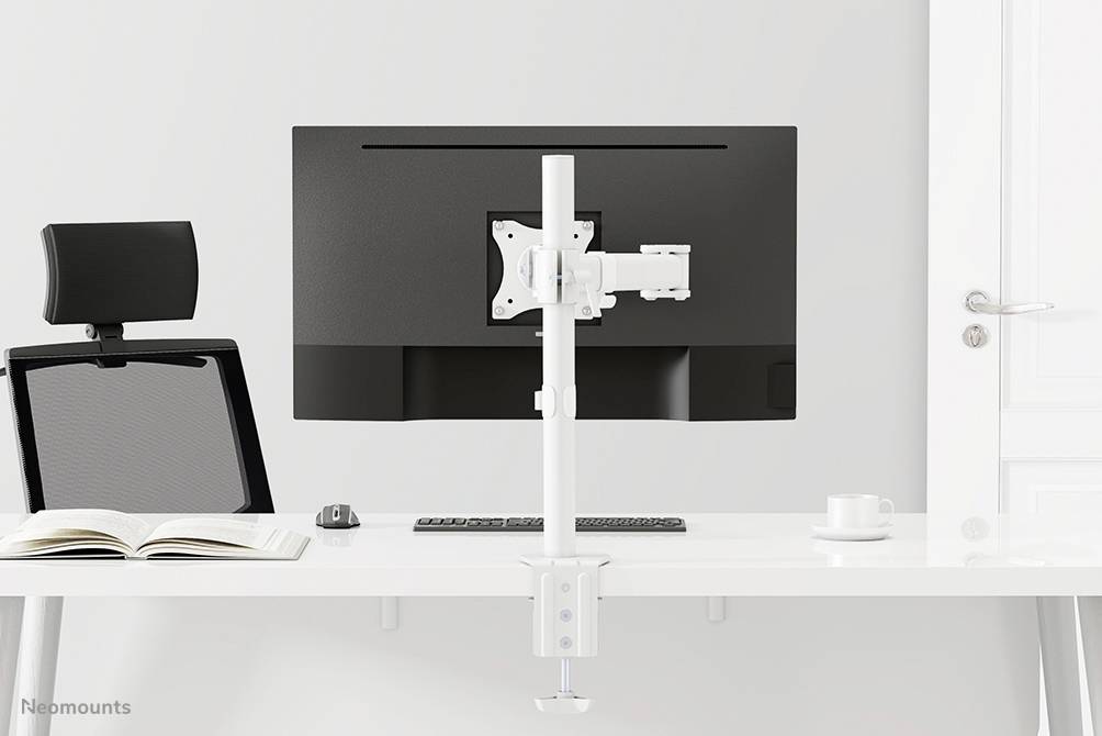 A minimalist workspace with a desk featuring a large monitor on a white stand, with a mug and a book beside it.