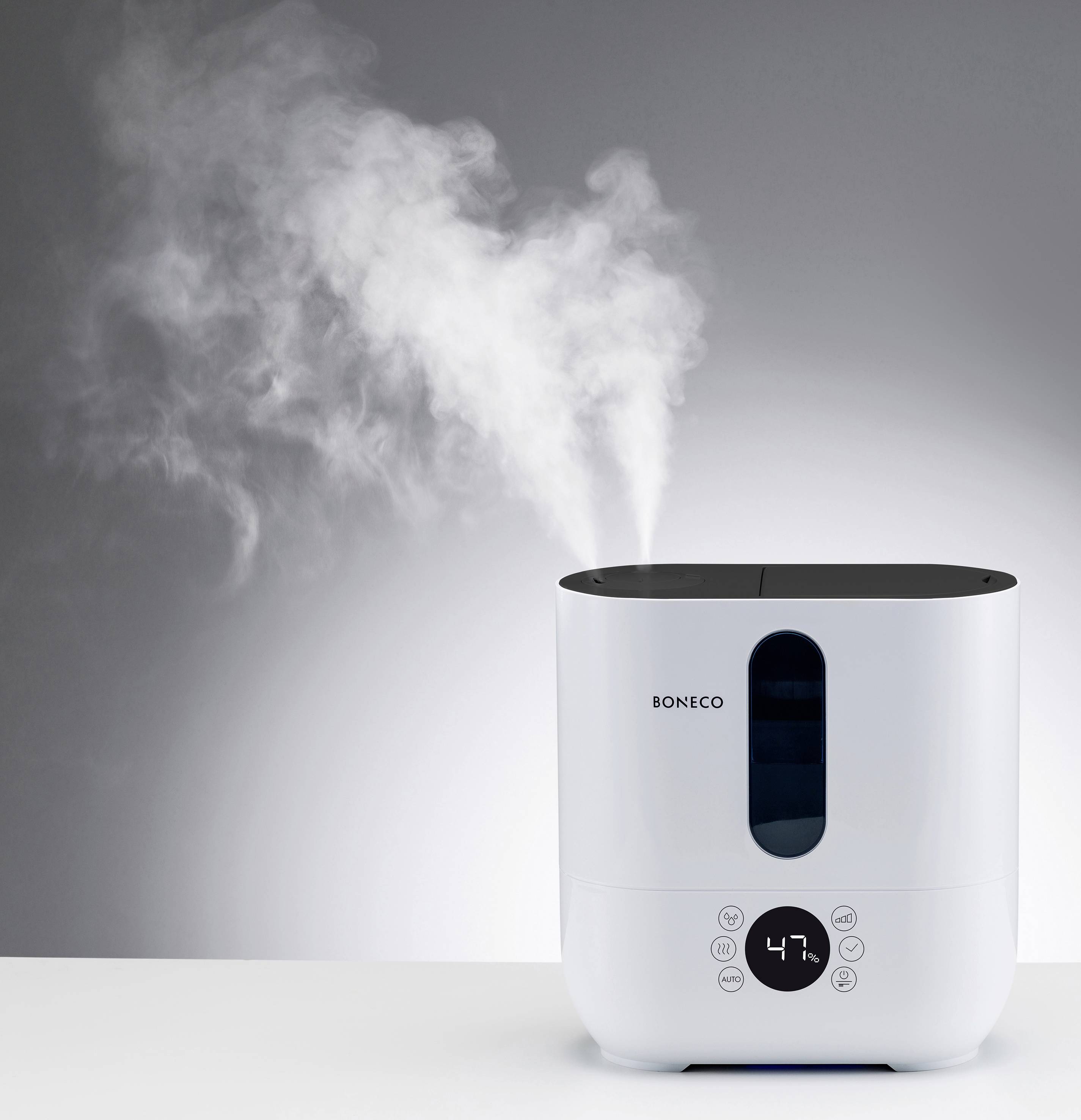 A white air humidifier with a digital display sits on a table, emitting steam. The brand name is "Boneco".
