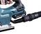 A hand is holding an electric saw with a hose connection for dust extraction. The saw is a Makita battery-powered model.