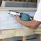 A person is applying sealant with a blue caulking gun to a window frame.