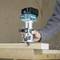 A person is working on a wooden board with a blue Makita milling tool, with wood shavings flying off.