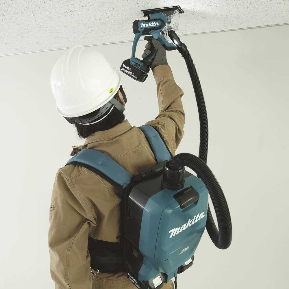 A person uses a Makita drywall sander on a ceiling while wearing a hard hat and backpack-style dust extractor for safety and efficiency.