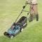 A person is mowing a lawn with a Makita electric lawnmower. The person is wearing gardening gloves and wellington boots.