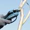 A person is cutting a branch with an electric pruning saw. The glove protects the hand from injuries.