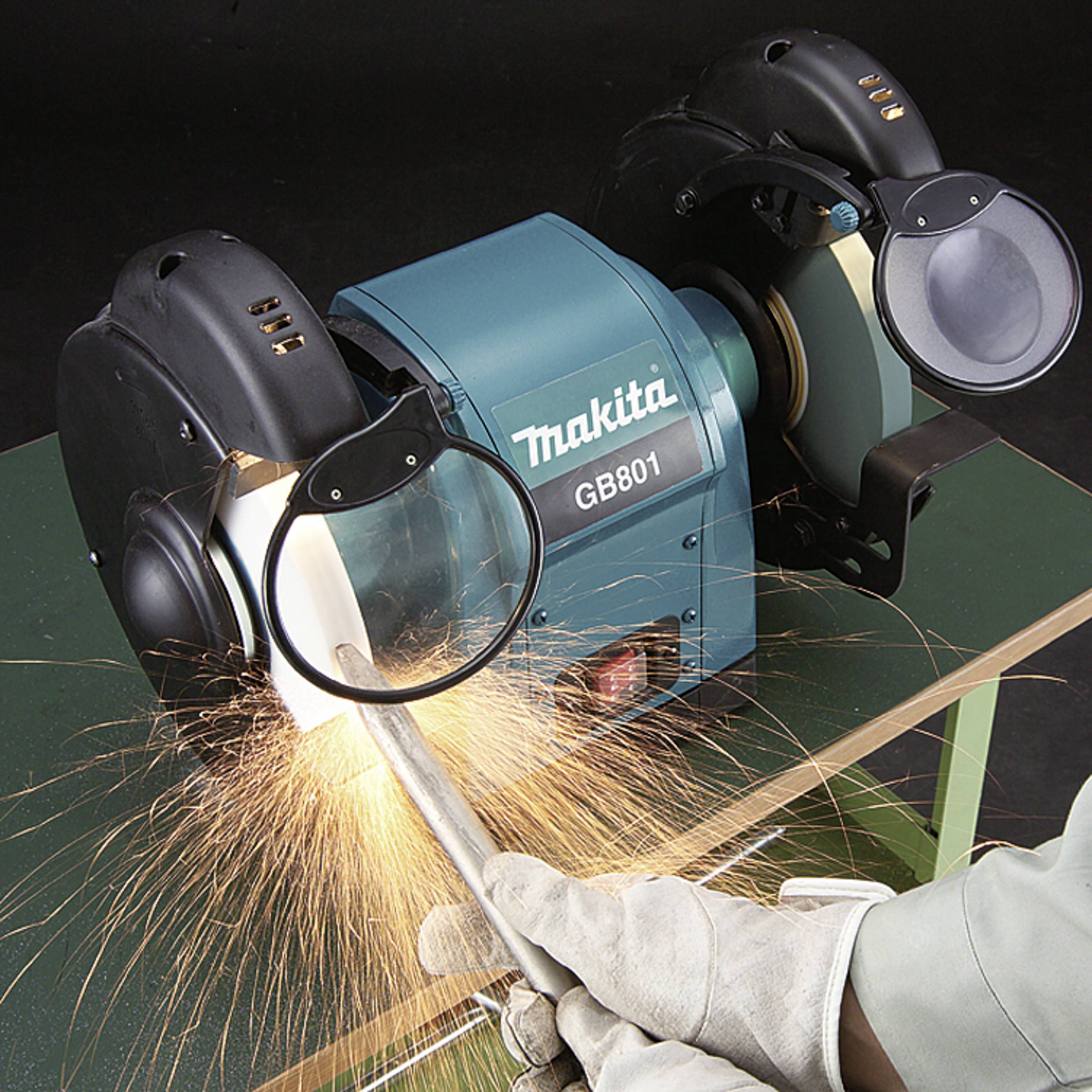 A person is grinding metal with a blue Makita GB801 grinding tool; sparks are flying. The device has a magnifying guard.