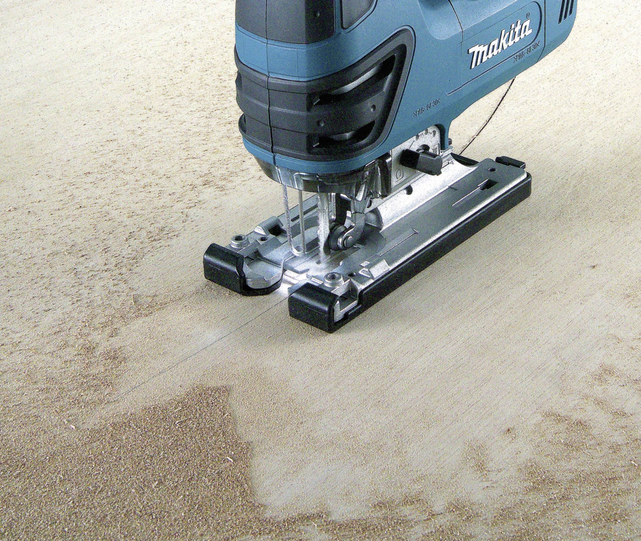 A blue jigsaw is cutting wood along a marked line on a workbench. Sawdust surrounds the cutting interface.
