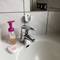 A washbasin with a tap, to the left a liquid soap dispenser bottle with a pink pump and a rectangular soap dish.