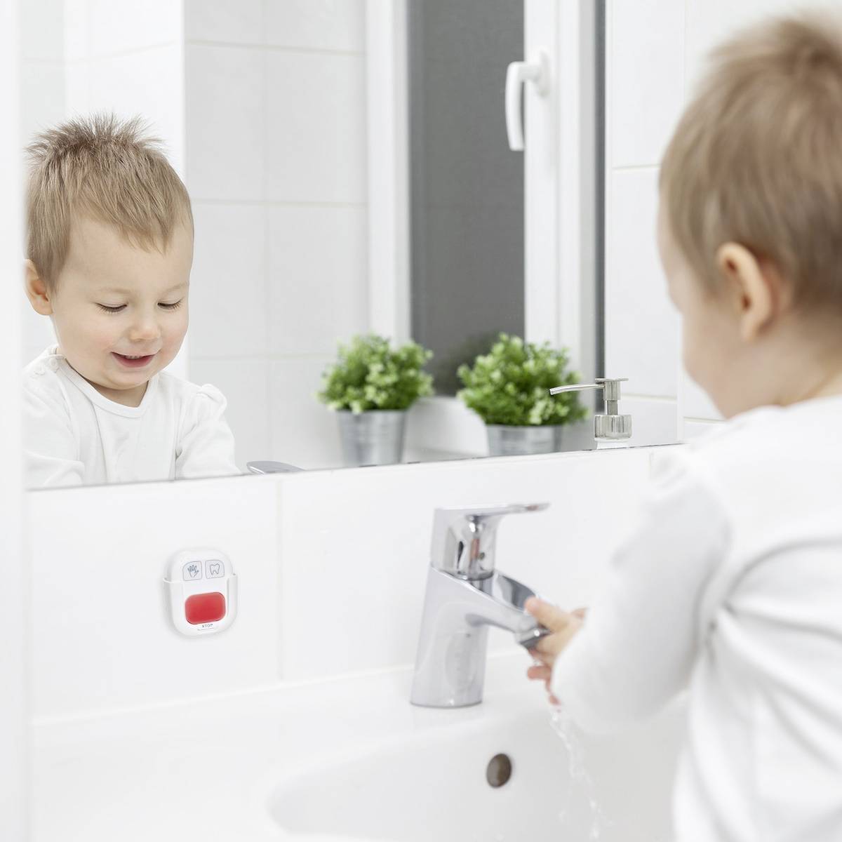A child stands by the sink and looks in the mirror. Two small plants are in the background.