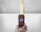 A hand holds a wood moisture metre over a piece of wood on a white background. The device displays measurement results.