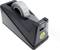 A black tape dispenser with transparent adhesive tape is placed on a smooth surface, with the tape partially unrolled.