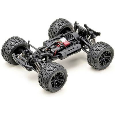 A remote-controlled car chassis with large, robust tyres and visible engine and suspension components on a light surface.