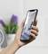 A person is holding a smartphone displaying an image of modern architecture. Blurred room decor is visible in the background.