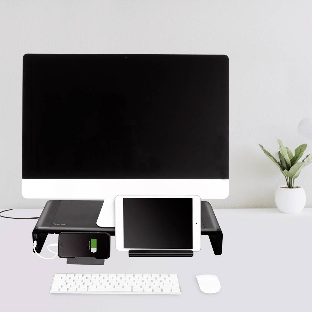 A tidy desk with a large computer monitor, a charging station underneath with a tablet, keyboard and mouse.