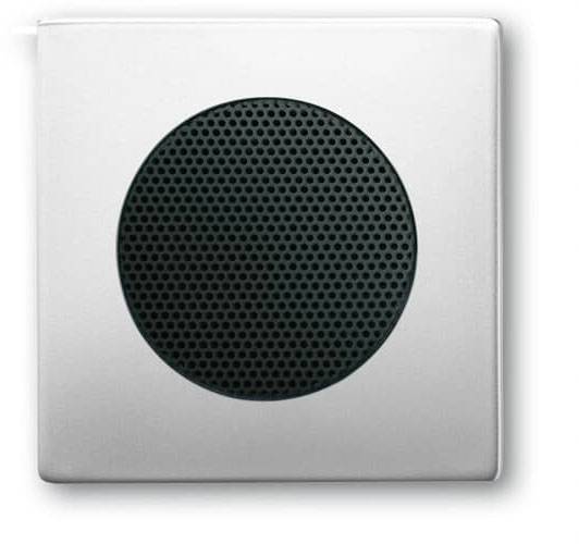 A square speaker with a black, round grille in the centre, mounted on a white wall.