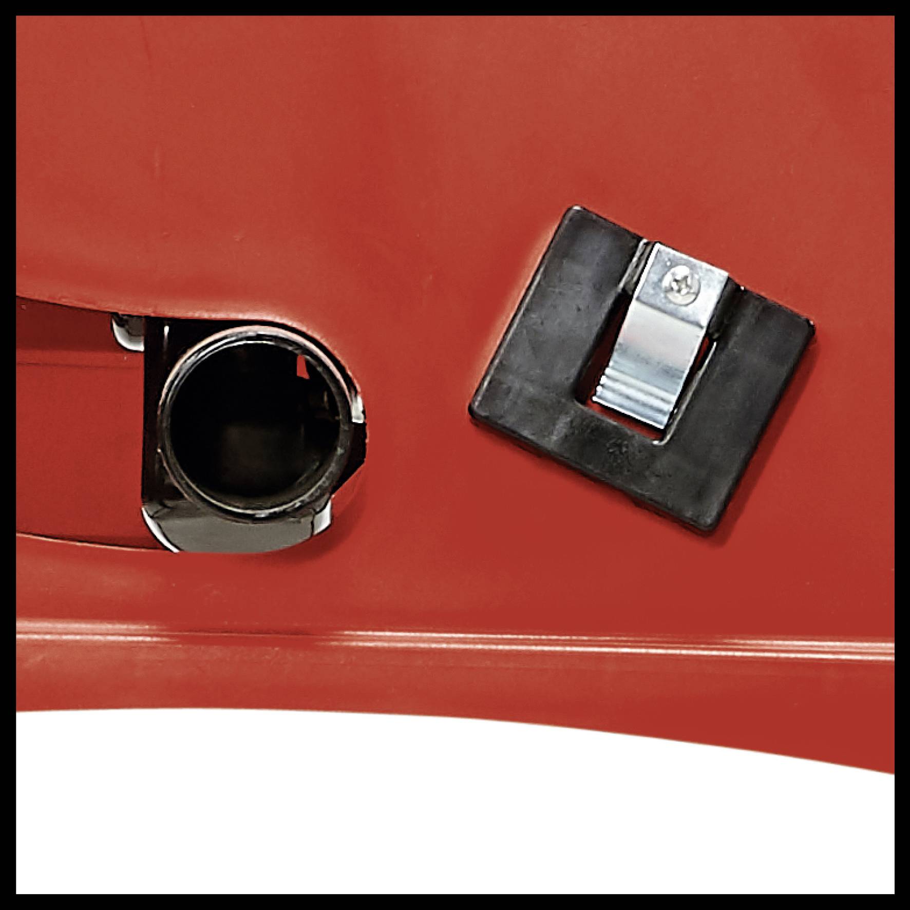 A red plastic object with a black rectangular bolt on the side. A silver metal component is partially visible.