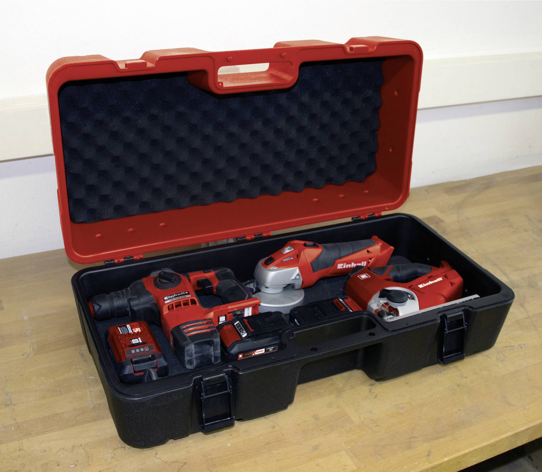 An open toolbox on a workbench, displaying various cordless power tools such as drills, grinders, and a battery.