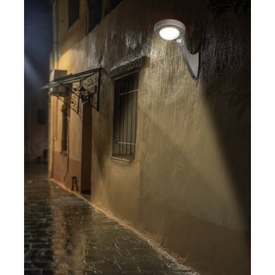 A lit alleyway at night. A street lamp casts warm light on a wet, deserted street beside a building.