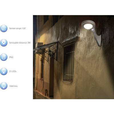 Outdoor area at night with illuminated wall lamp with motion sensor. Left technical details: Sensor range 120°, distance 3m, IP65, 21 LEDs, 1000 lumens.