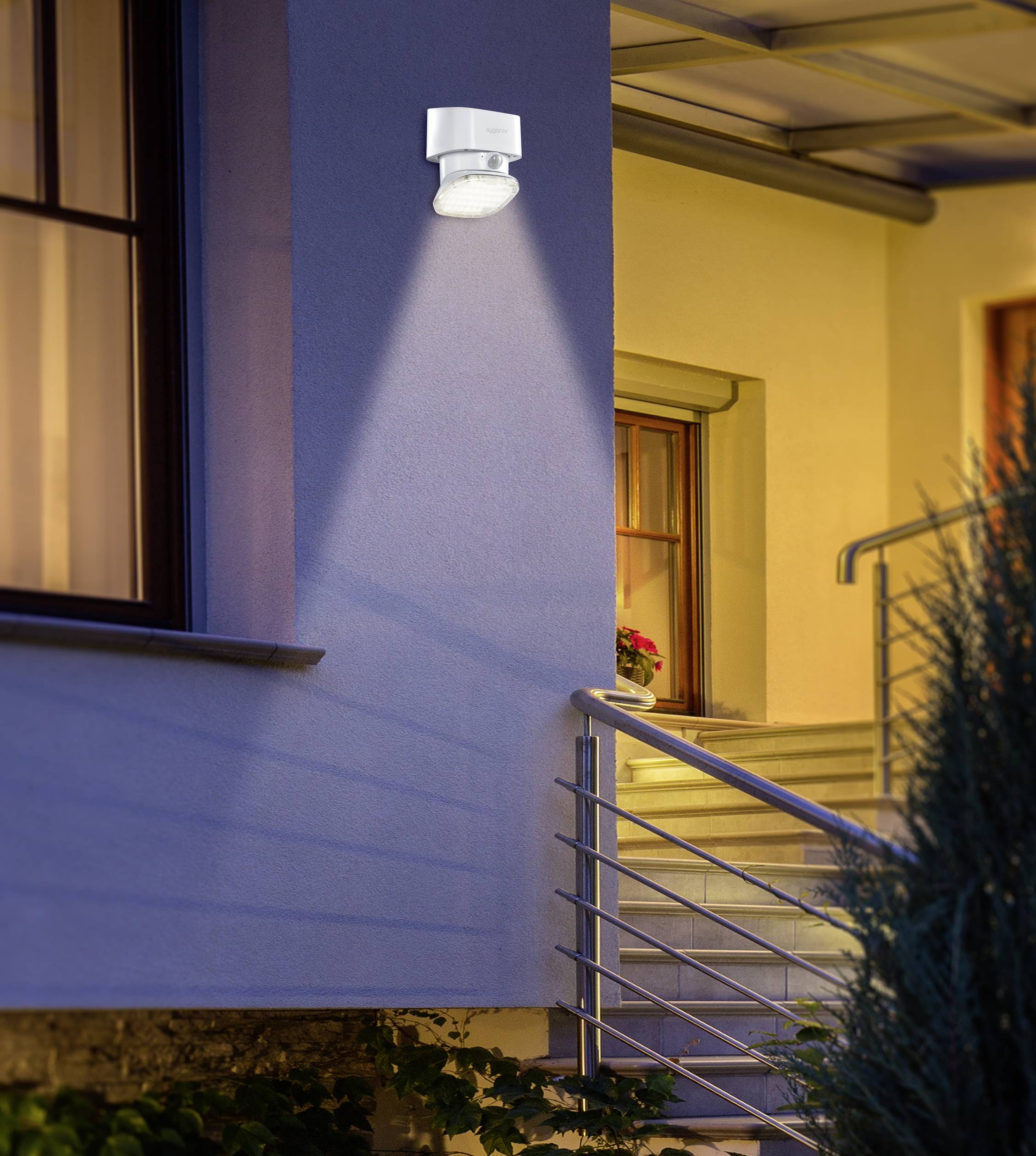 Outside light with motion sensor illuminates blue house entrance at night, with stairs and railings in the background.