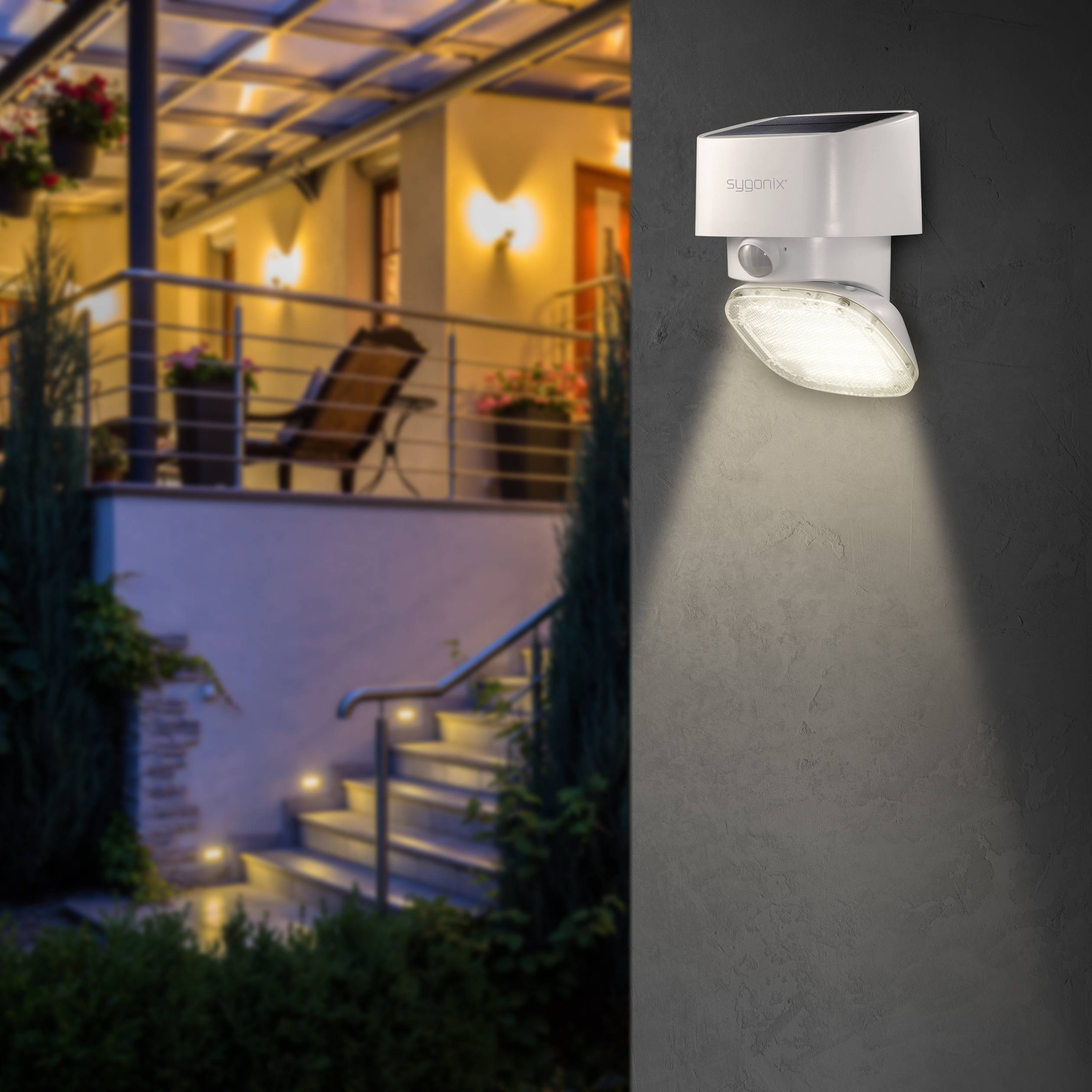 An exterior lamp with a motion sensor illuminates an evening terrace with hanging flower baskets and steps.