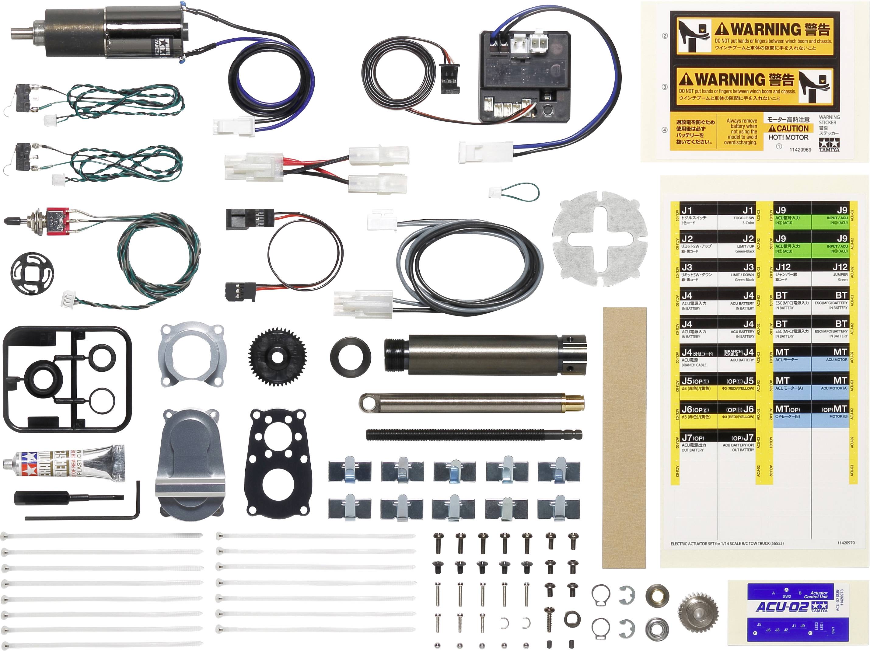 Various parts of a technical kit are laid out in an orderly manner on a surface, including motors, cables, screws, and instructions.
