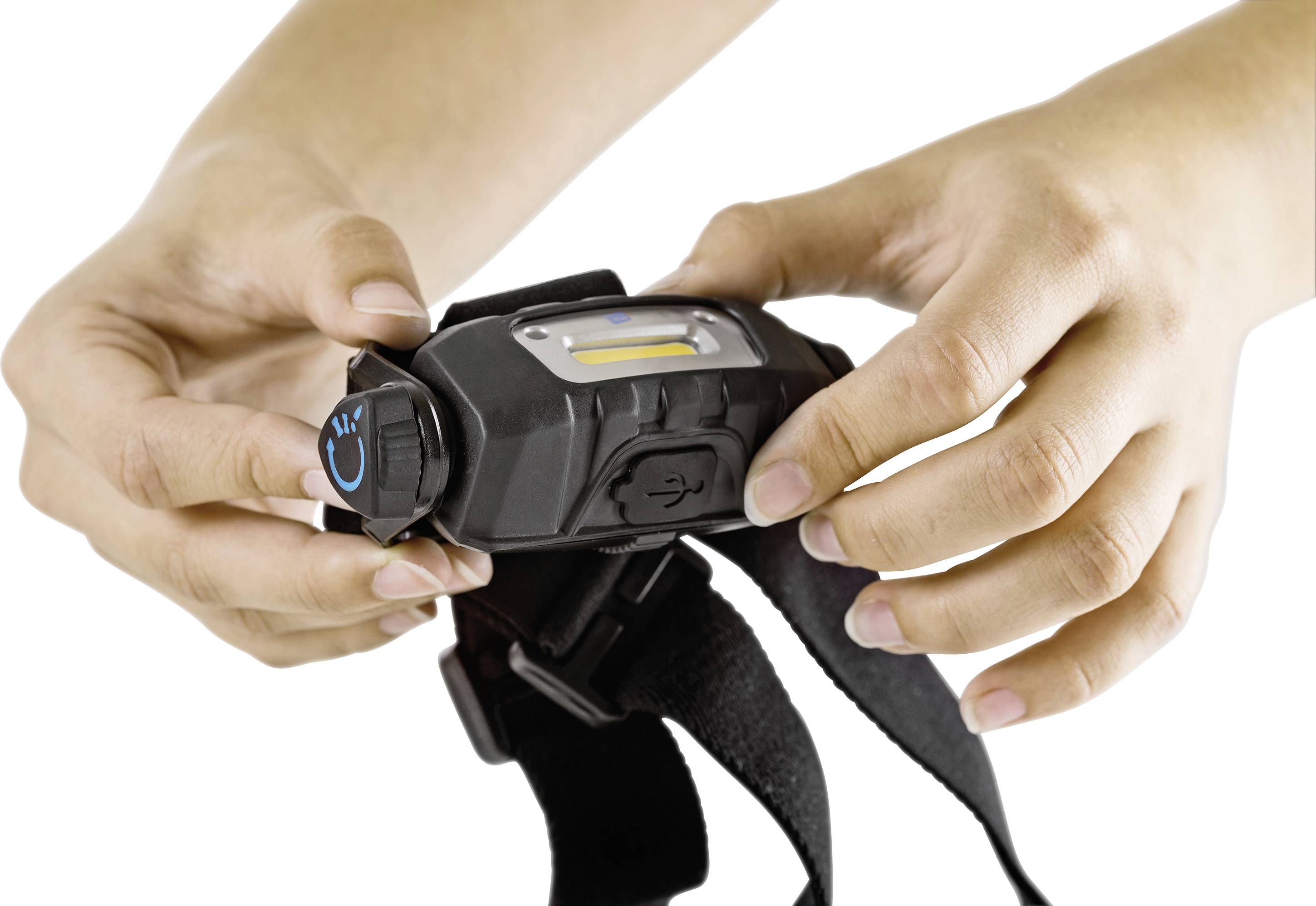 Hands are holding a head torch with an adjustable strap and USB port.