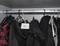 Several jackets hang on coat hangers in a wardrobe. A white label with the inscription 'CARDIGO' is visible.