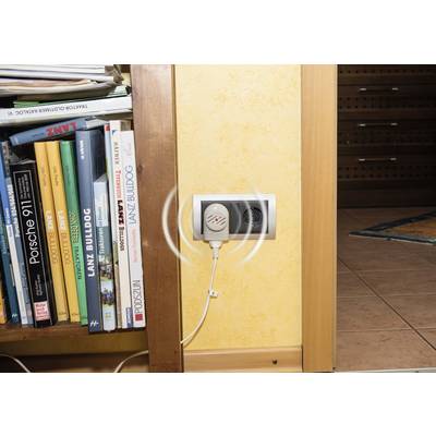 Bookshelf full of books next to a wall socket, with an electrical device plugged in.