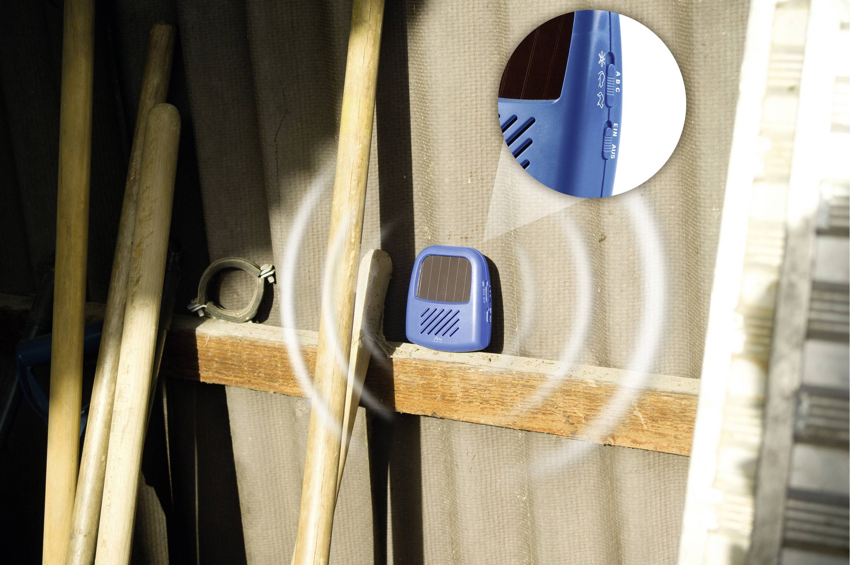 A blue device in the shed is emitting signals. It is hanging on a shelf with broom handles and indicating that it is active.