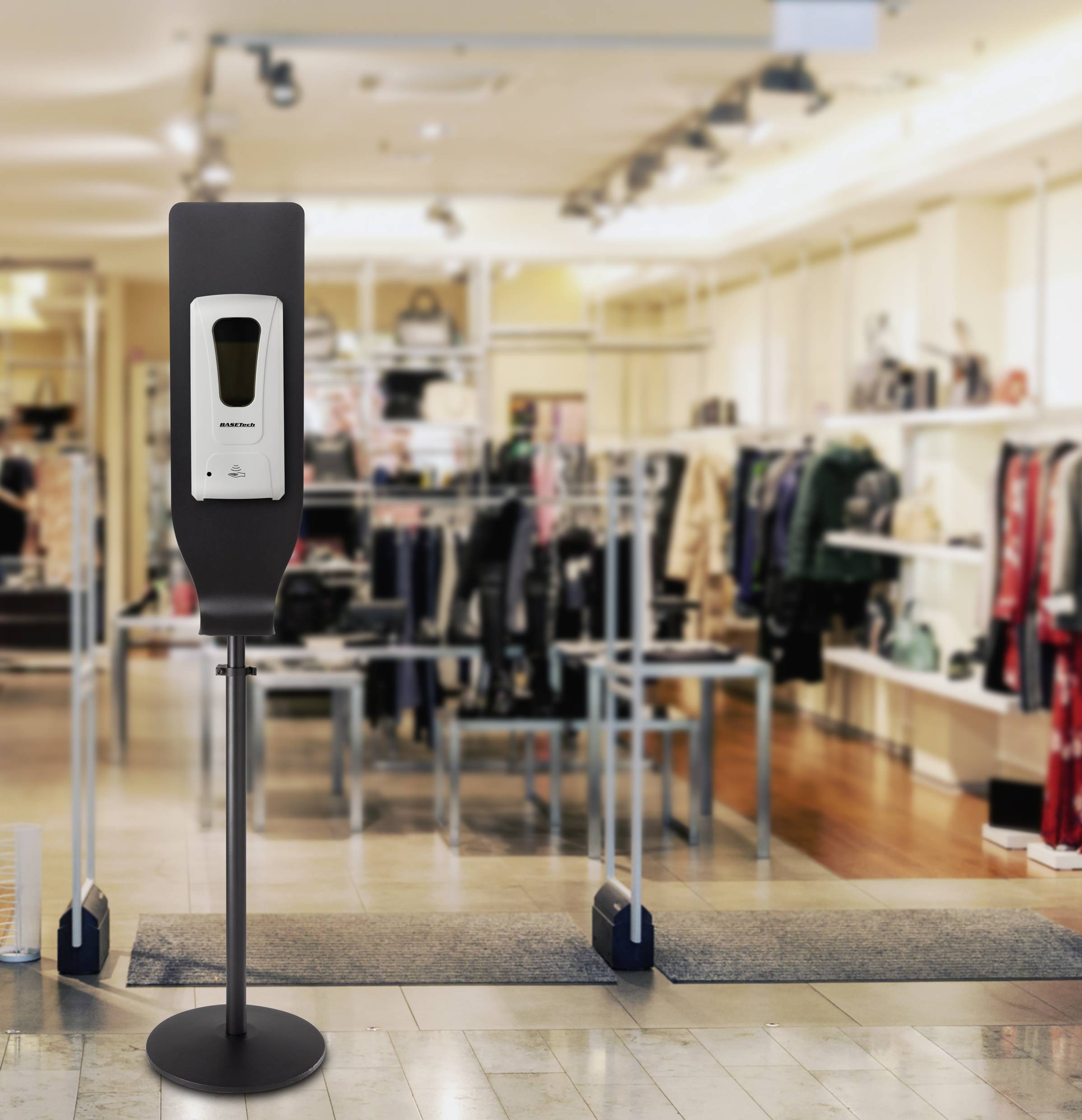 Hand sanitiser dispenser in a clothing store. Clothing racks in the background. Safety measure for hand hygiene.