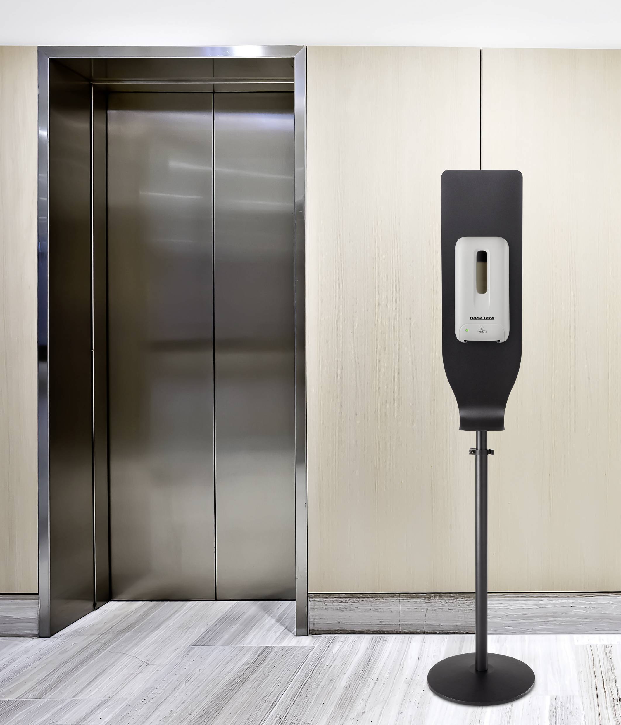 A hand sanitiser dispenser stands next to a closed lift in a modern building.