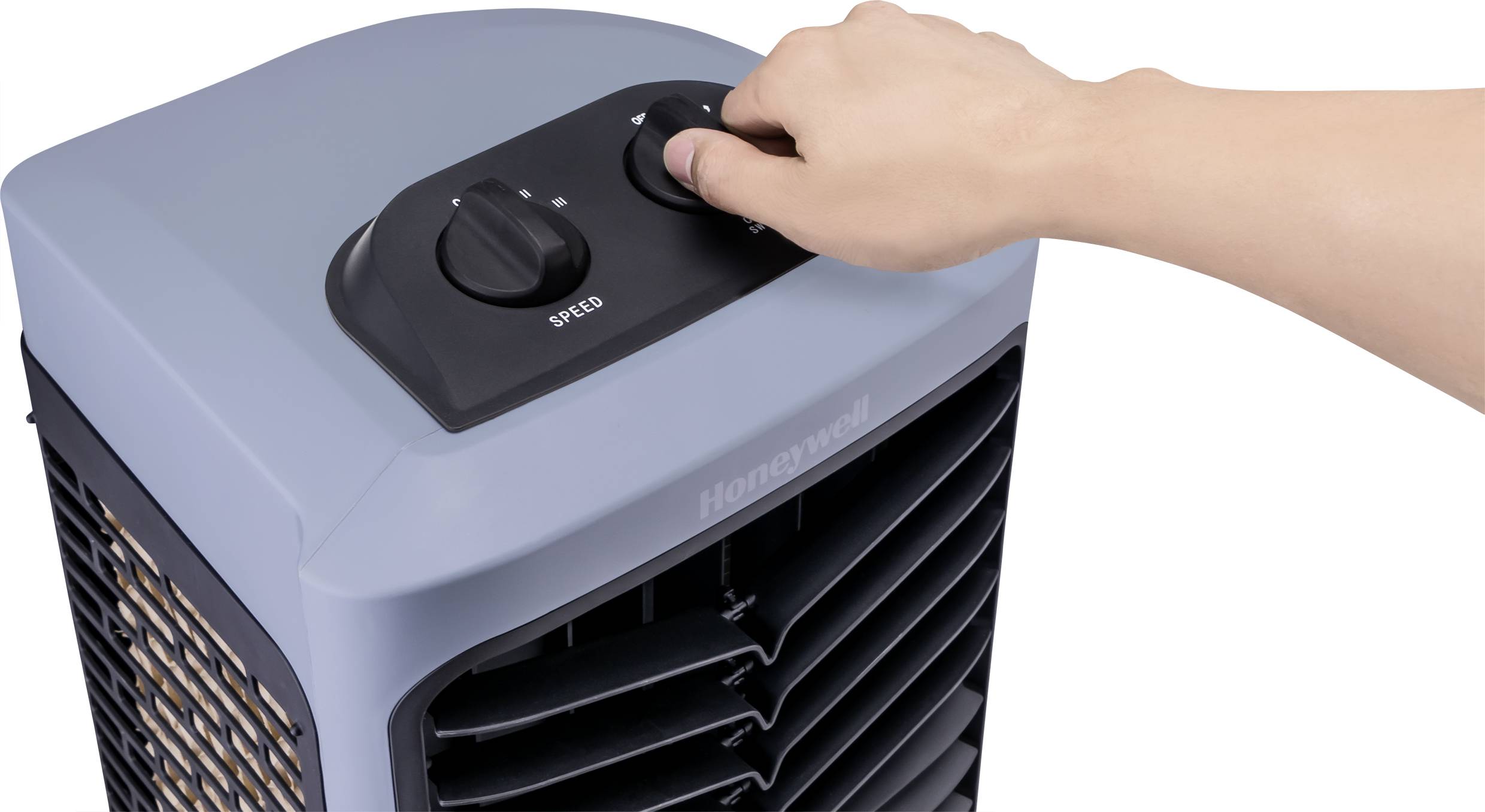 A hand turns the speed dial of a grey air cooler.