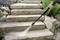A person uses a pressure washer to clean stone steps surrounded by rocks and plants, showing effective outdoor cleaning.