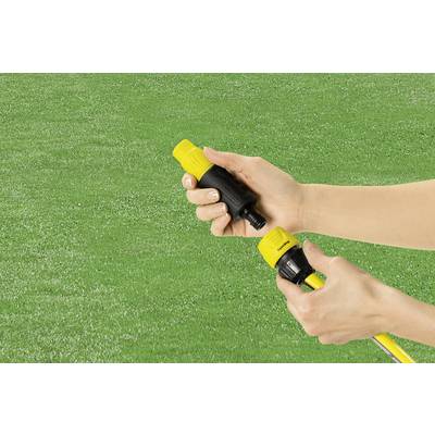 Hands are connecting two yellow garden hose connectors against a green lawn background.