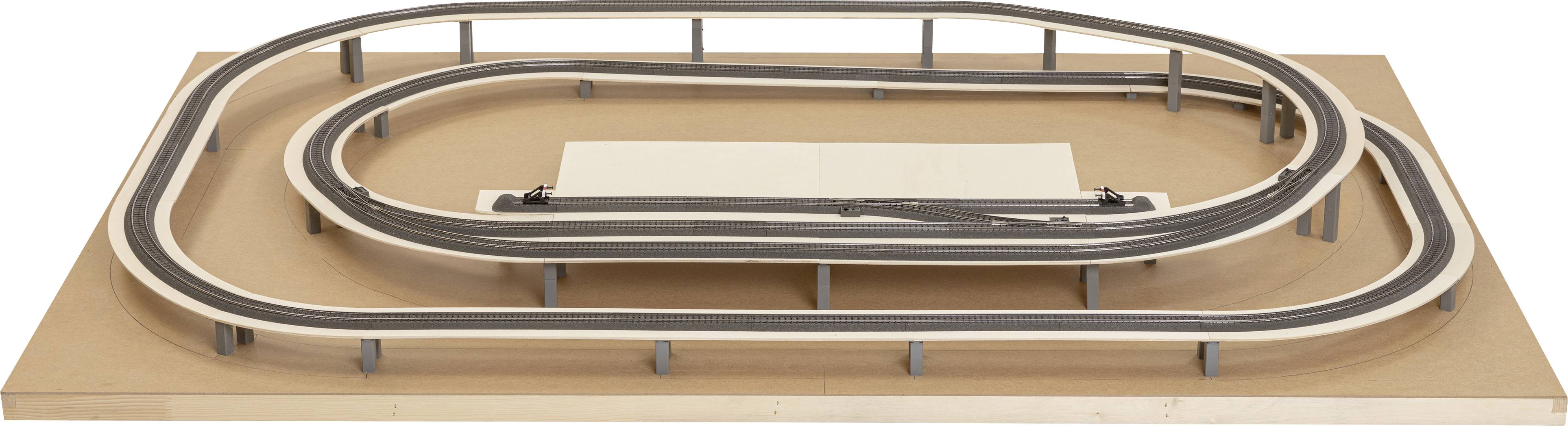 A model railway layout with a two-track oval track network on a wooden board.