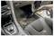 A person vacuuming the floor of a car's interior, removing debris from the carpet.