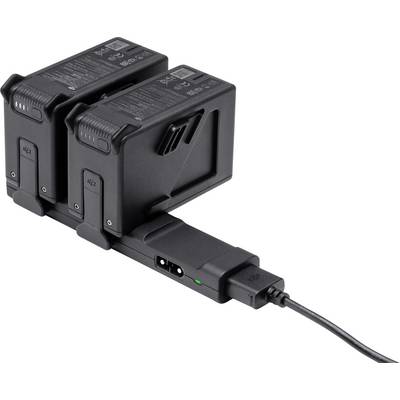 Two black batteries are connected in a dual charger and are being charged via a cable. A green LED indicates the charging status.
