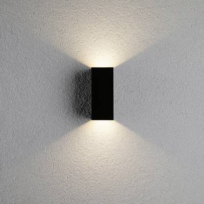 Wall light casts warm light upwards and downwards onto a grey wall, creating a symmetrical pattern.