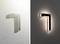 'Two L-shaped wall lights: Left in white, right in black. Both cast soft light against the wall and create a modern effect.'