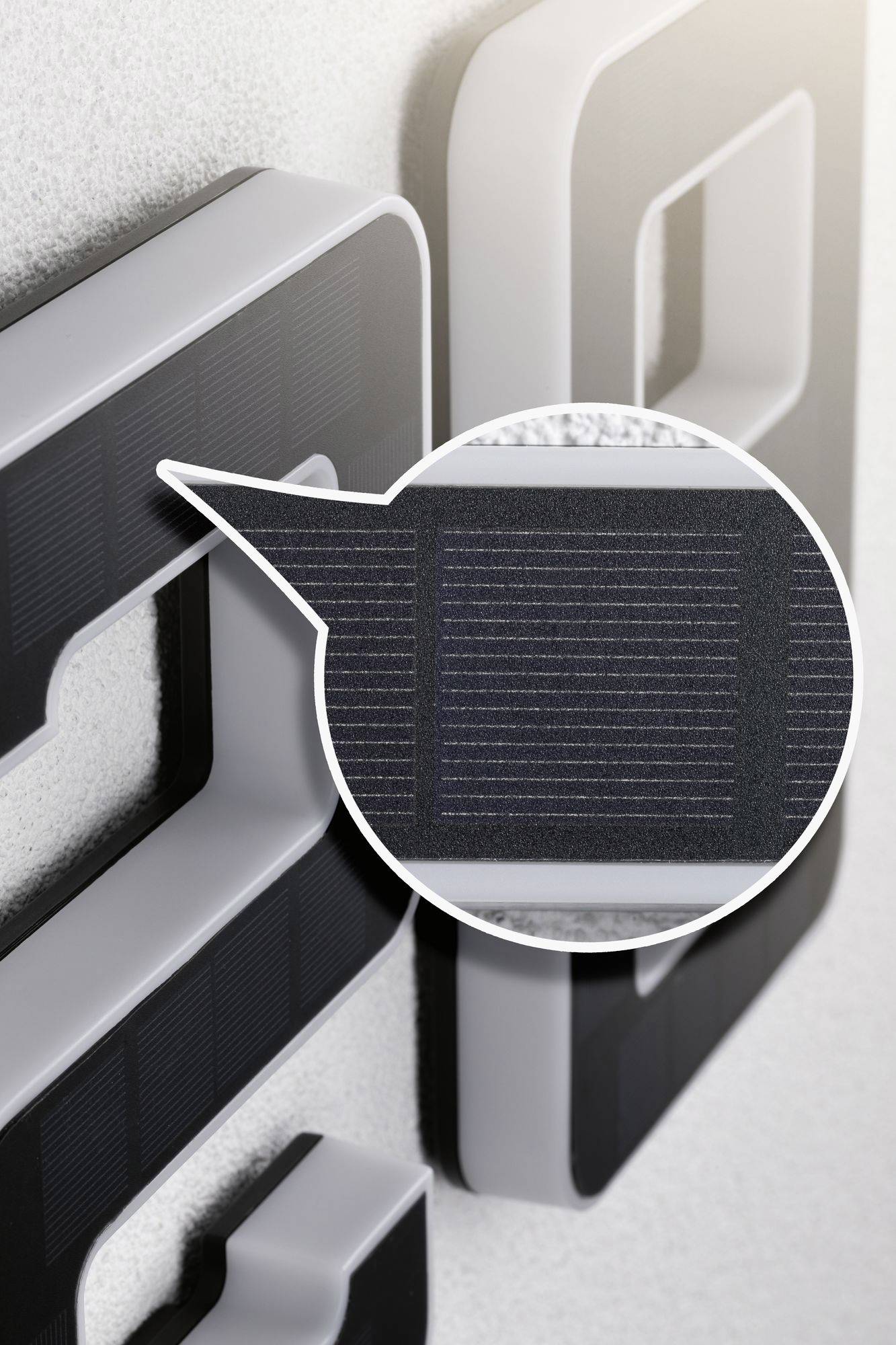 White house number with integrated, detailed solar panels on a grey background. Close-up reveals panel structure.