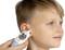 A child is having their temperature taken with a digital ear thermometer. The display shows '37.3°C'. The child is smiling slightly.