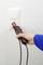A hand is testing the electrical voltage of a socket with a voltage tester against a white wall.