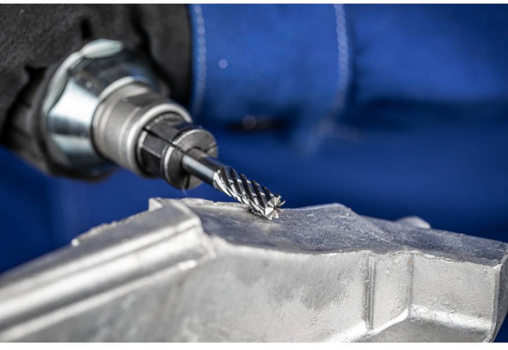 'Close-up of a drill bit machining metal.' The scene depicts a milling process with a metal workpiece.