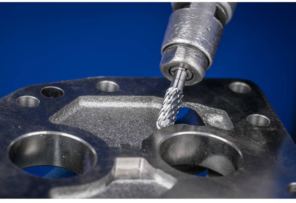 Milling tool precisely machines metal plate with holes. Close-up shows detailed machining during industrial manufacturing process.