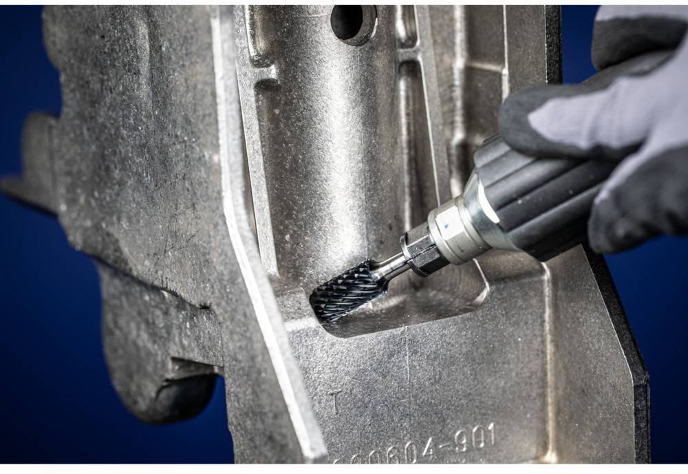 A person is polishing a metal surface with a rotating tool to remove burrs and smooth the surface.