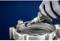 A gloved hand holds a rotating tool grinding metal from a component. Blue background.