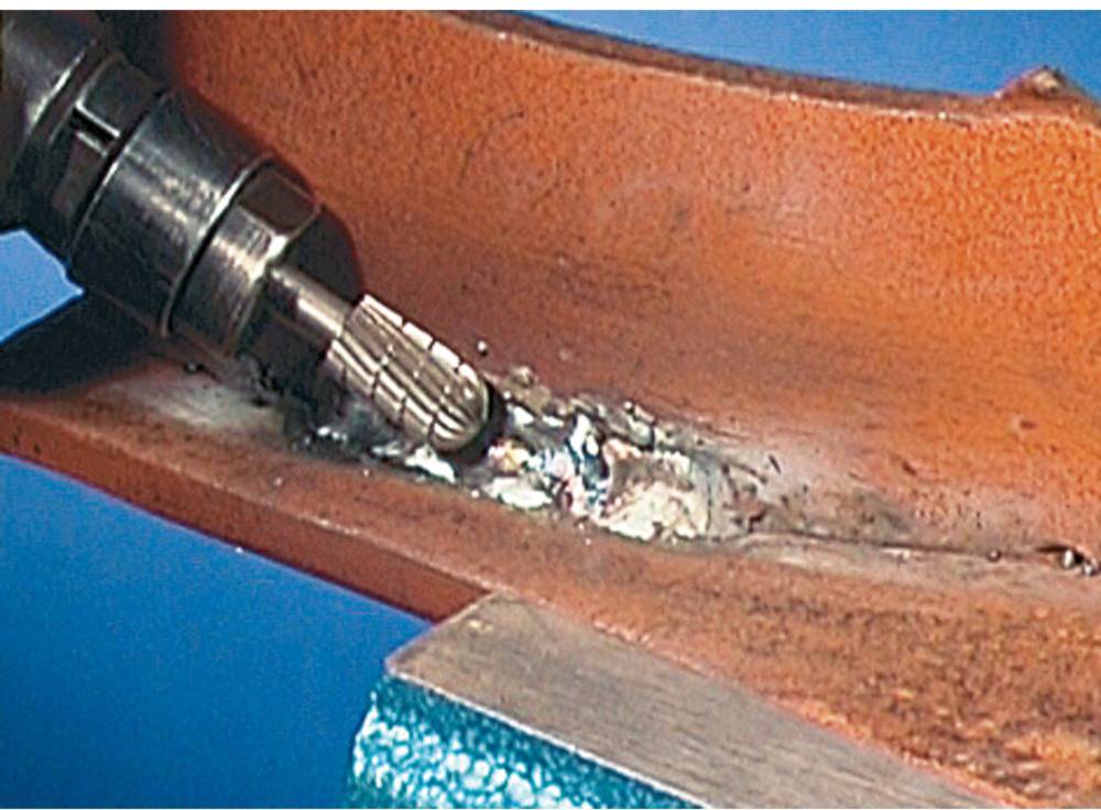 'A drill removes weld seams from a metal surface.'