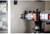 A drill is piercing the wall of an electrical control panel. The drill bit is visible at an angle from the side.
