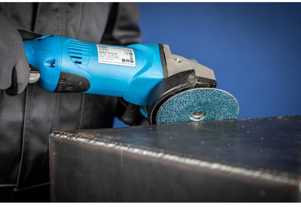 A person is polishing a metal surface with a blue angle grinder. The grinder has a greenish-blue grinding disc.