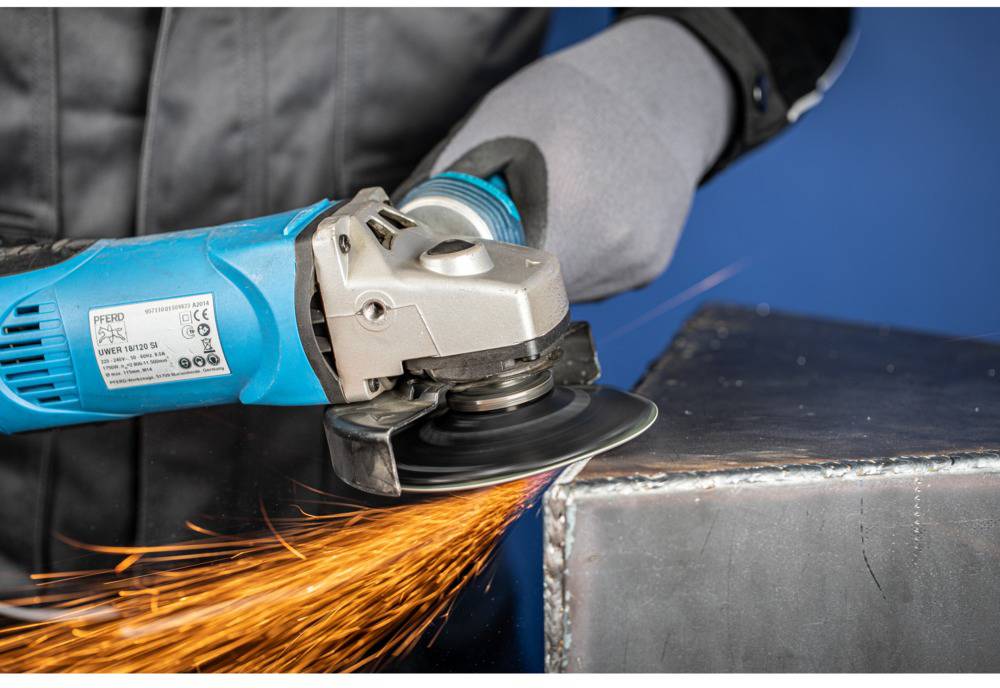 A person is grinding metal with a blue angle grinder. Sparks are flying as the edge of the metal piece is being worked on.